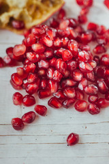 Pomegranate peel and seeds over white wooden background.