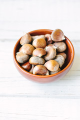 Raw chestnuts in ceramic bowl.