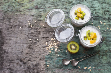 Breakfast yogurt with oatmeal and orange Kiwi fruit on a wooden background top view