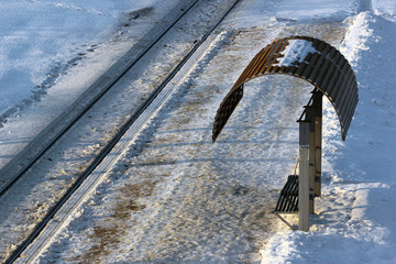 Empty tram stop with rails at winter evening