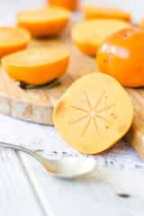 Half of persimmon fruit on wooden board.