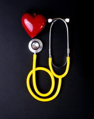 Closeup of a stethoscope and red heart on black background