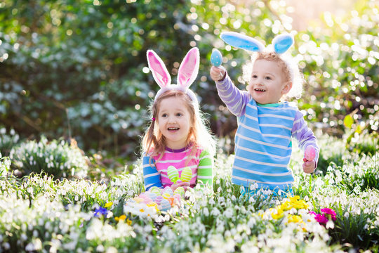 Kids on Easter egg hunt in blooming spring garden