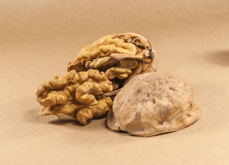 Fototapeta na wymiar Walnut kernels and whole walnuts on kraft paper, close up, horiz