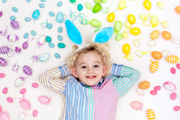 Obraz na płótnie Canvas Child on Easter egg hunt. Pastel rainbow eggs.