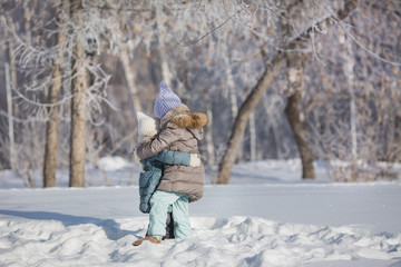 Fototapeta na wymiar Two little sisters hug each other in snow in winter