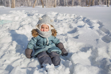 Fototapeta na wymiar Portrait of little baby sits on snow in winter