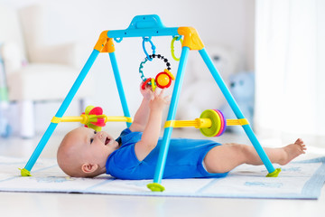 Baby boy on play mat. Child playing in gym.