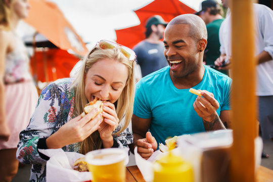 couple having fun time eating burgers and drinking beer