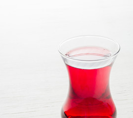 Hibiscus tea in a glass mug on a wooden table among rose petals and dry tea custard