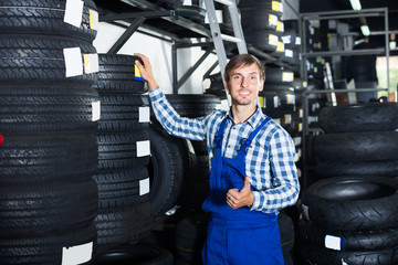 Fototapeta na wymiar smiling mechanic man working with car tires in workshop