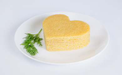 Pile of pancakes in the shape of a heart on plate with sprig of