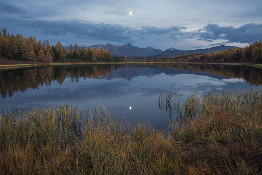 Mirror Surface Lake Autumn Landscape With Mountain Range In Early Eveing With Stars On The Sky