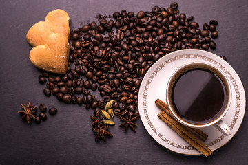 Coffee cup, coffee beans and biscuits, cookies in the shape of heart on wooden background