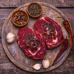 Raw Beef Steak, salt, pepper, garlic, rosemary  on the wooden board, background.