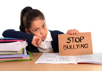 young cute hispanic schoolgirl scared in stress holding paper with text stop bullying - obrazy, fototapety, plakaty