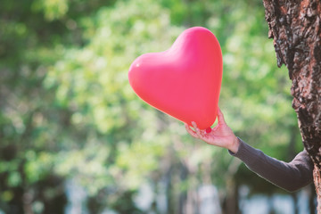 Heart-shaped balloon in the hands of a woman. Idea and concept for Valentine's day.