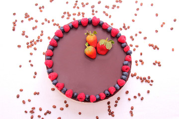 Cake souffle, covered with chocolate, jewelry, berries, raspberry, blueberry, blueberry, strawberry, white background.
