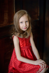 Portrait of a cute young redheaded girl sitting on a chair
