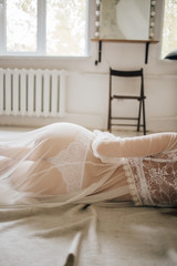 girl in a white gown boudoir robe lying on the floor with her back and ass to the camera in lace panties