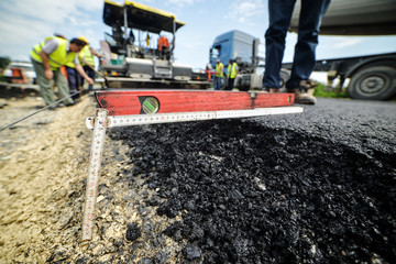 Heavy duty road building. Hot Asphalt being laid and measured fo