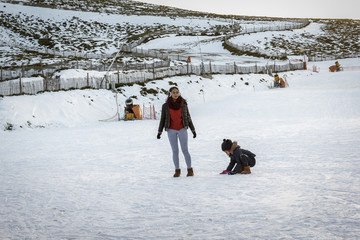 Una niña y su hermana adolescente divirtiéndose en la nieve.