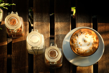 the sun foam design in hot latte coffee and suger on rough wooden table