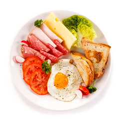 Breakfast - toasts, fried egg and sausages, cheese, ham and vegetables 