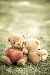 two bear dolls and red heart in human hand, select focus the one bigger