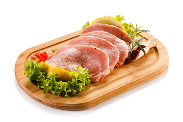 Raw pork chops on cutting board and vegetables 