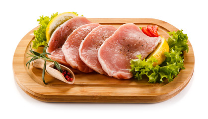 Fototapeta premium Raw pork chops on cutting board and vegetables 