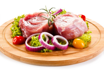 Raw meat on cutting board and vegetables 