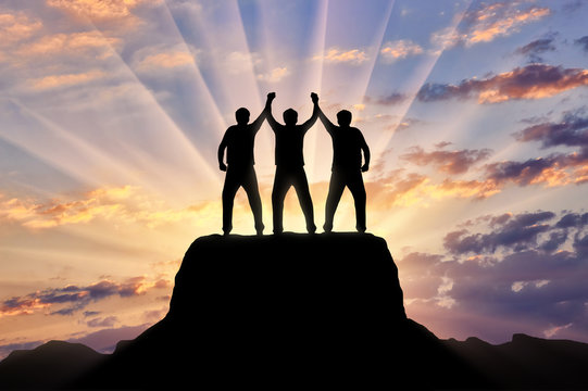 Silhouette Of Happy Three Climbers On The Top Of The Mountain