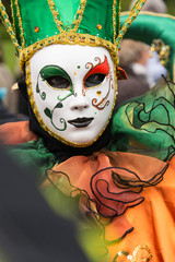 Masques de venise et costumes de carnaval. Ton orange et vert. Regard triste.
