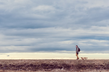 Hiker and dog walking in grassland