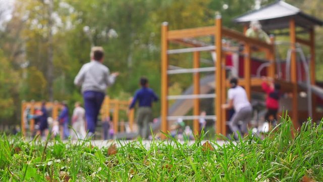 Children and parents having fun on playground in park. Selective focus on foreground, slow motion.