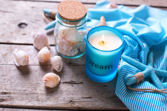 Blue candle and marine items on  aged wooden background.