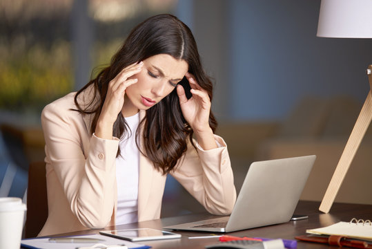 Hard day in the office. Shot of a young businesswoman looking stressed while sitting in her office in front of laptop.