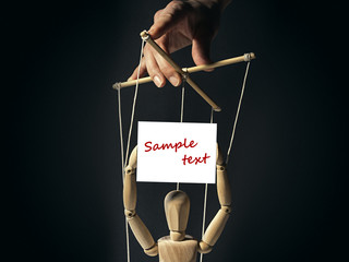 Tiran holds on the strings of a puppet in the hands of the doll banner with free space for your...