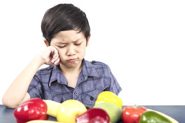 Asian boy is showing dislike vegetable expression over white background