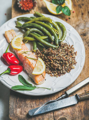 Healthy protein rich dinner plate. Oven roasted salmon fillet with multicolored quinoa, chilli pepper and poached green beans on rustic wooden board. Clean eating, weight loss, dieting food concept