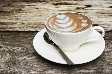Vintage hot coffee cup with nice Latte art decoration on old wooden texture table