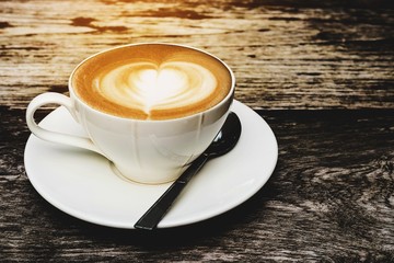 Vintage hot coffee cup with nice Latte art decoration on old wooden texture table