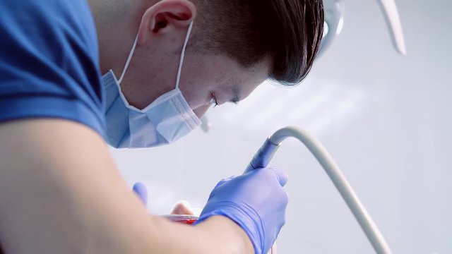 Asian doctor carrying out a procedure for the treatment of the patient's teeth. Bright clinic room .