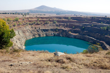 Abandoned open ore mine pit partially full of water