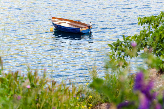 Empty blue boat moored in crisp clear waters of lake or sea