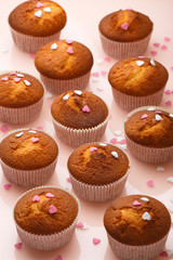 Muffins in paper forms and a lot of small sugar hearts on a mirrored background. Valentine's Day breakfast