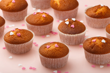 Muffins in paper forms and a lot of small sugar hearts on a mirrored background. Valentine's Day breakfast