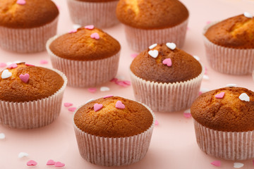 Muffins in paper forms and a lot of small sugar hearts on a mirrored background. Valentine's Day breakfast