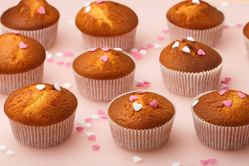 Muffins in paper forms and a lot of small sugar hearts on a mirrored background. Valentine's Day breakfast